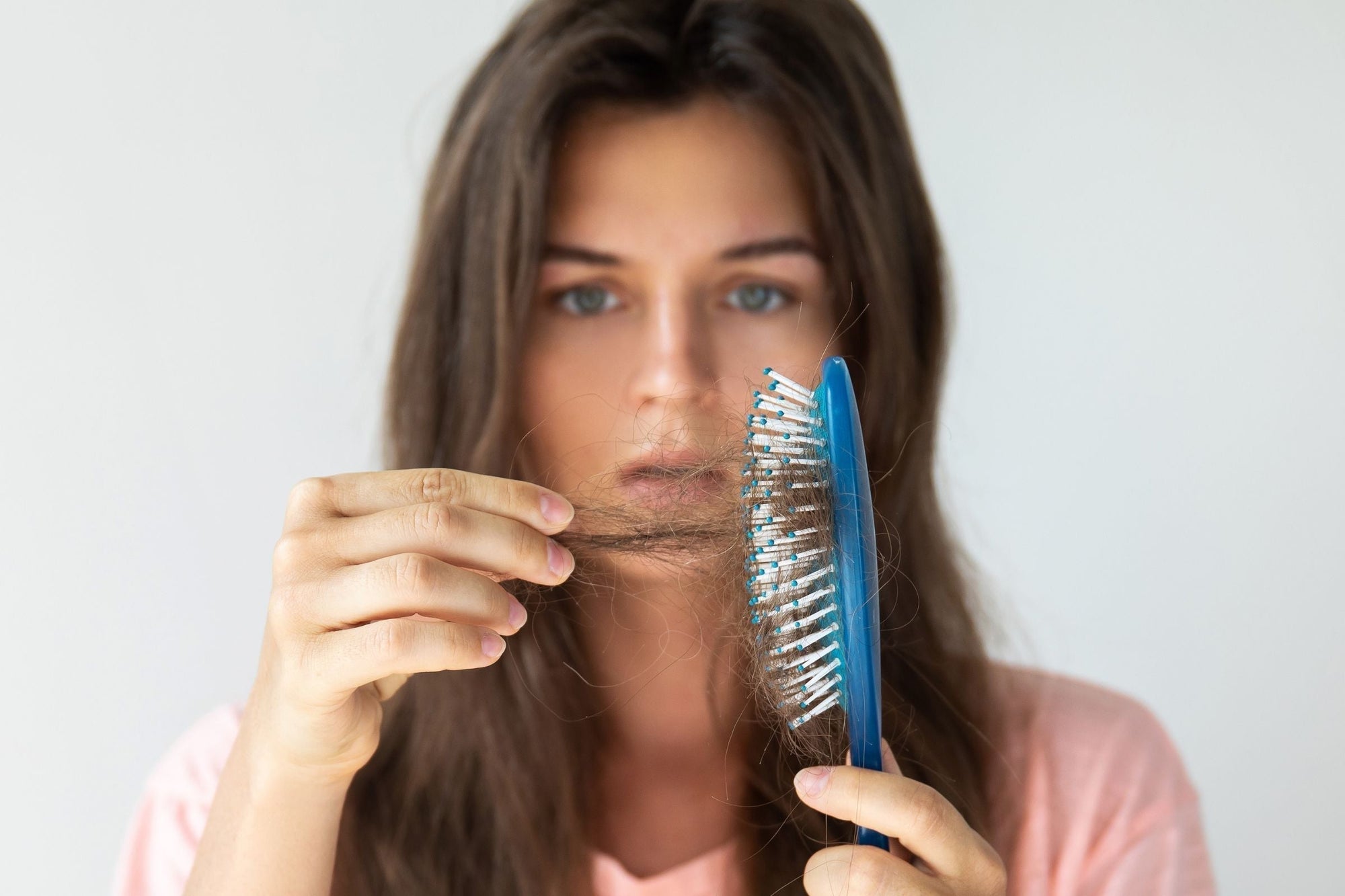 Woman noticing hair loss in her hair brush