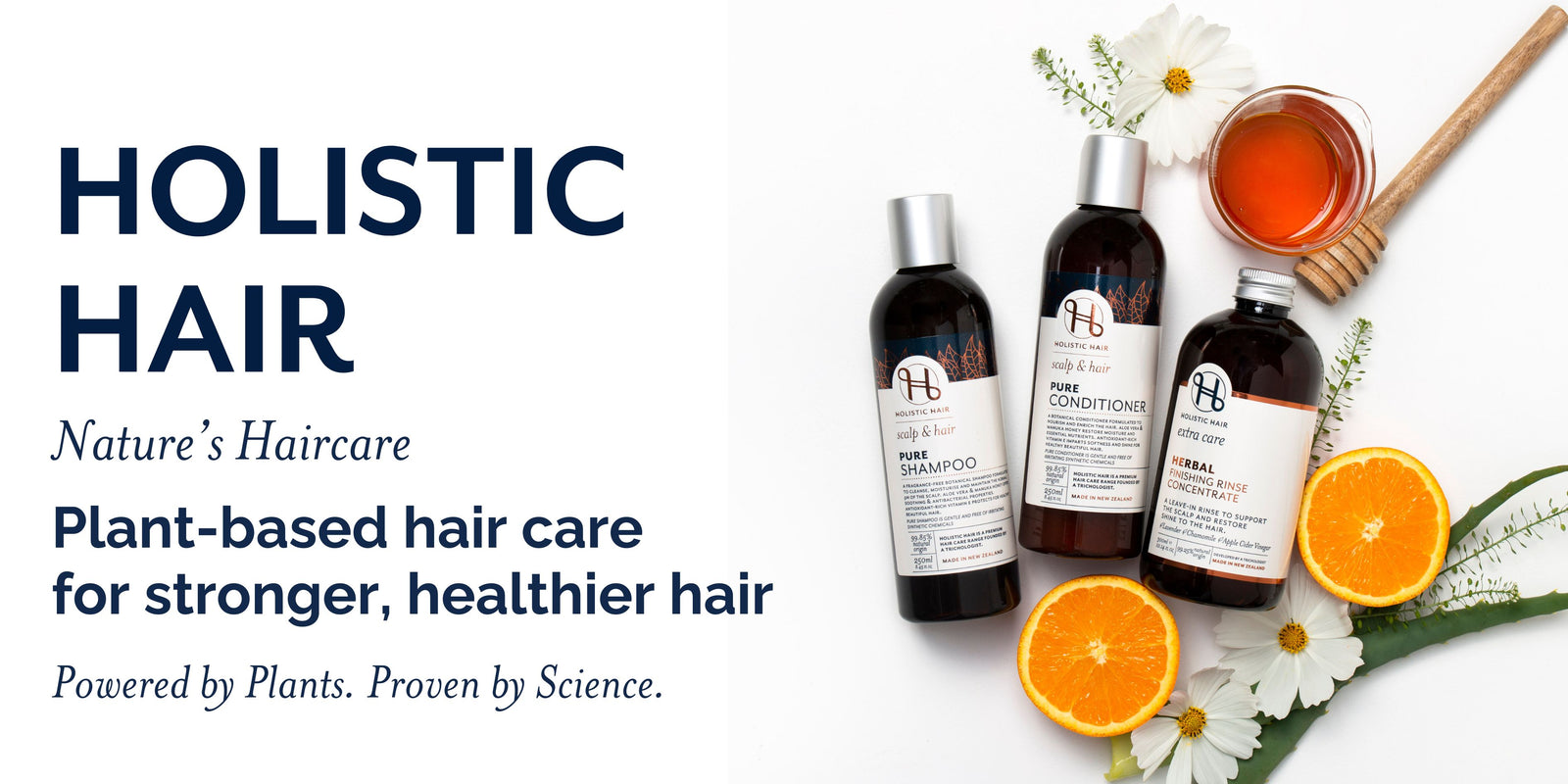 Holistic Hair hair care products with bottles, oranges, and flowers on a white background